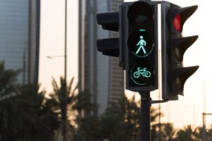 Traffic light showing pedestrian and bicycle signals with Abu Dhabi skyline backdrop.